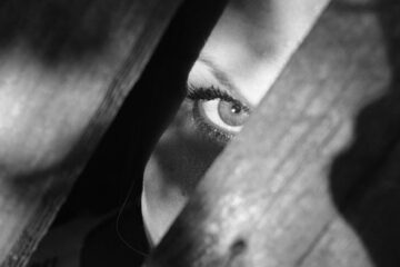grayscale photo of woman peeking on planks