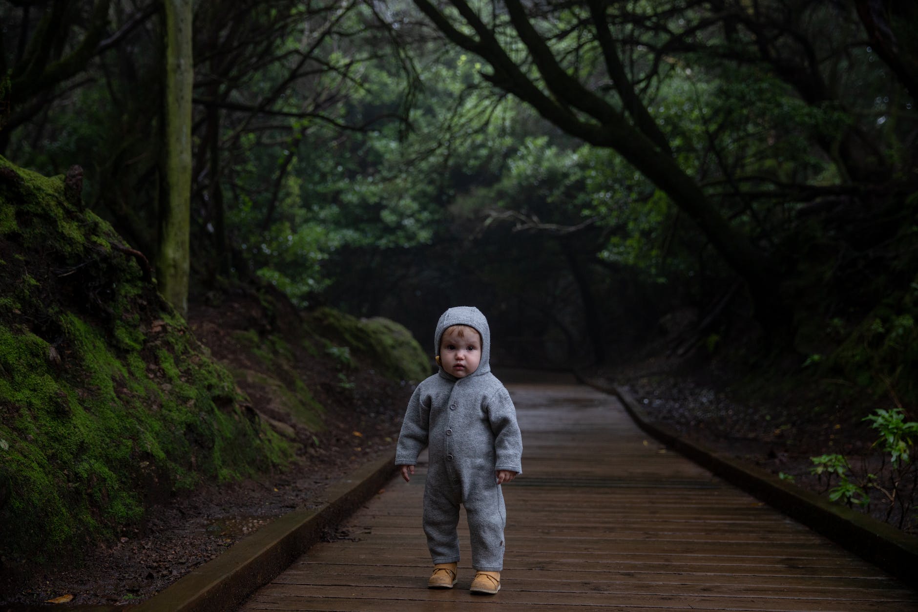 small kid standing on planked footpath