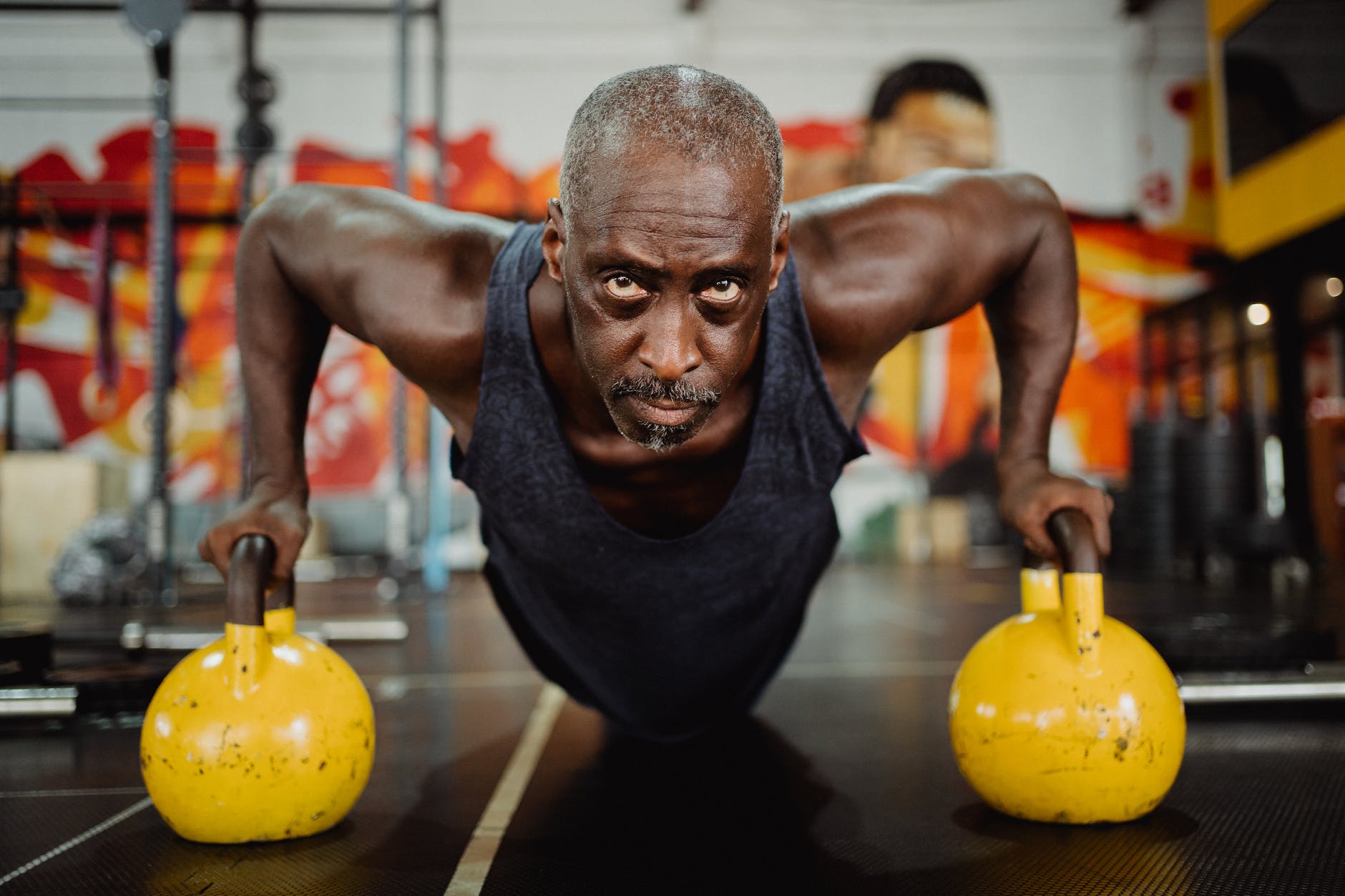 photo of man doing push ups using yellow kettlebell