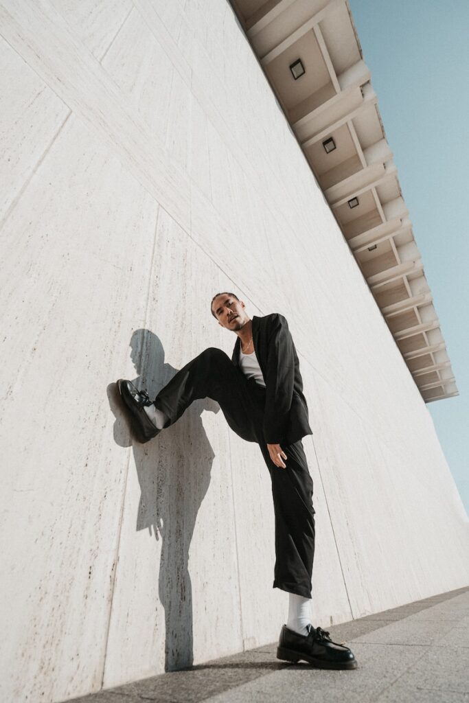 a man leaning against a wall with a skateboard