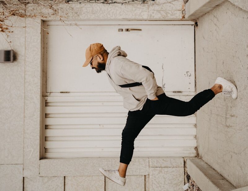 man in white long sleeve shirt and black pants jumping on white concrete wall during daytime